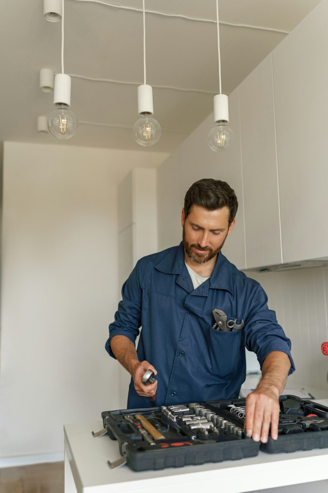 Professional handyman with tool bag standing on home kitchen background